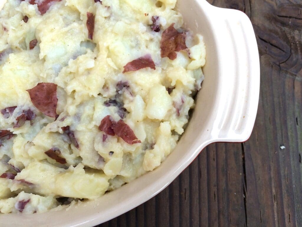 Mashed potatoes with bacon in a bowl on a wooden table.