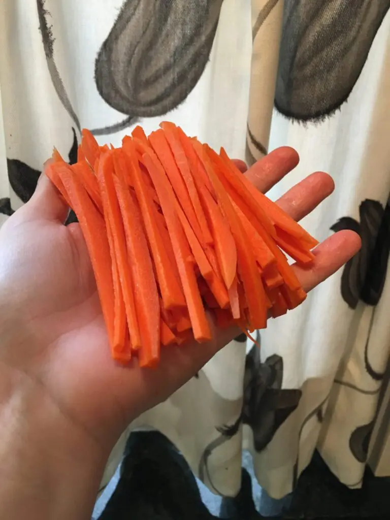 A person holding a bunch of carrots in front of a shower.