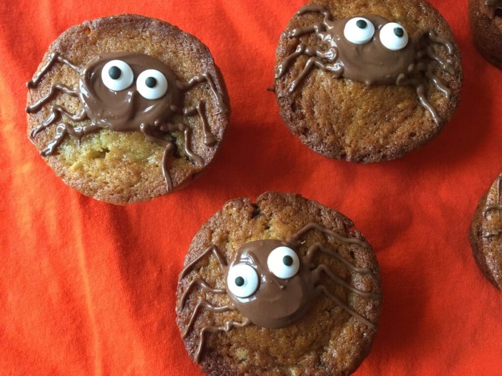 A group of cupcakes with chocolate spiders on them.