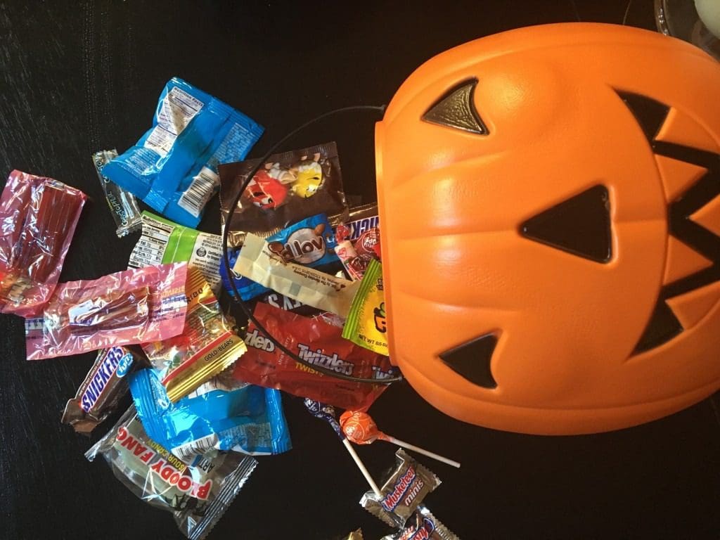 A halloween jack o lantern filled with candy.