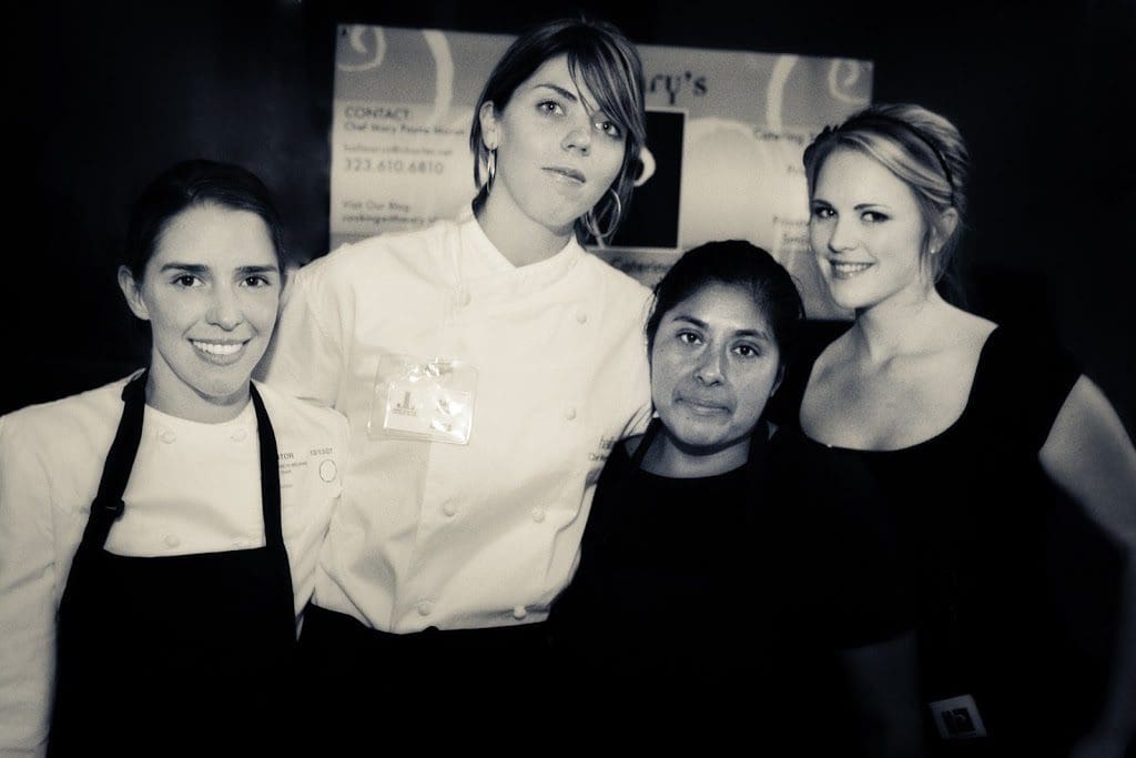 Four women in chef aprons posing for a photo.