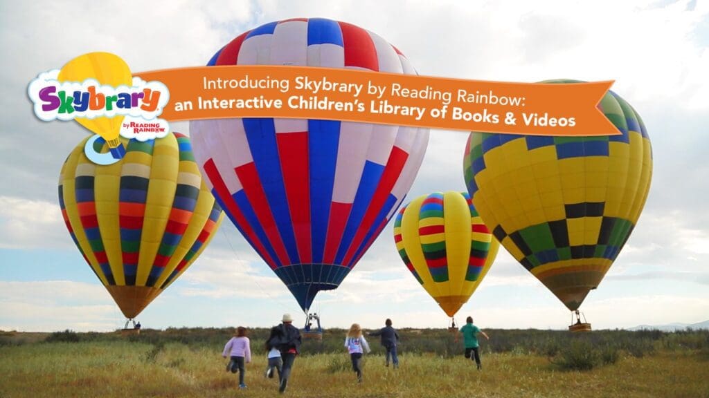 A group of people standing near hot air balloons.