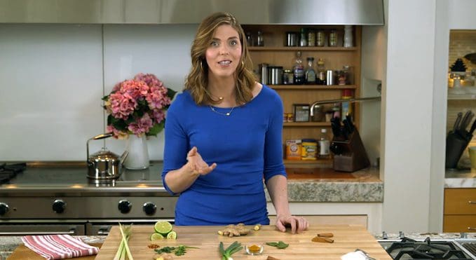 A woman in a blue shirt is preparing food in a kitchen.