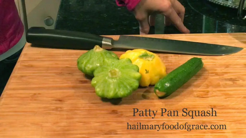 Patty pan squash on a cutting board with a knife.