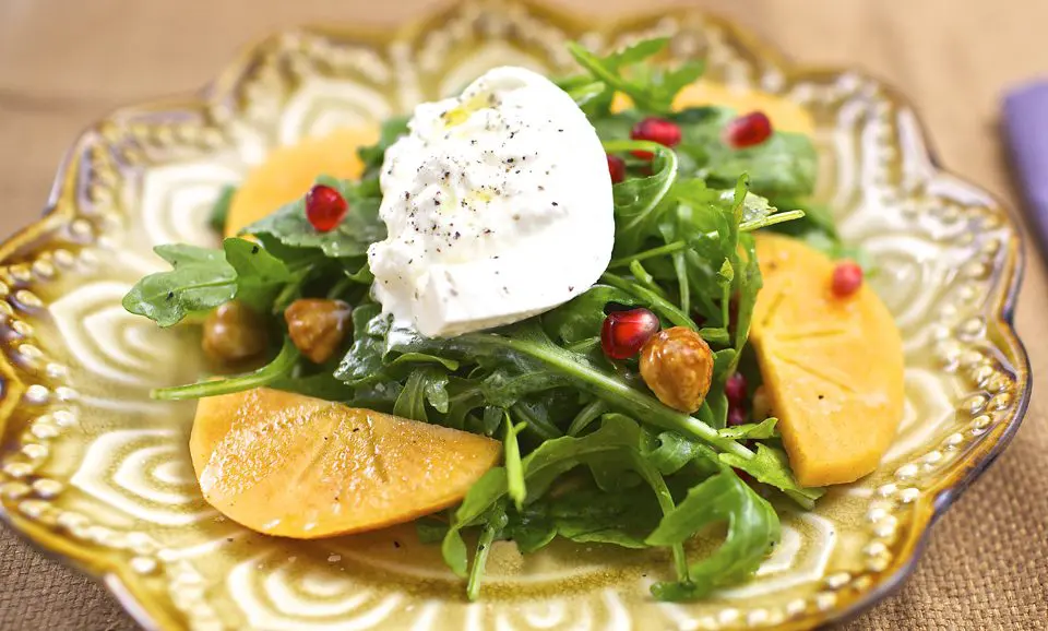 Pomegranate arugula salad with goat cheese and pomegranate seeds.