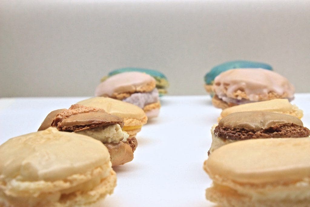 A group of macarons are lined up on a white plate.