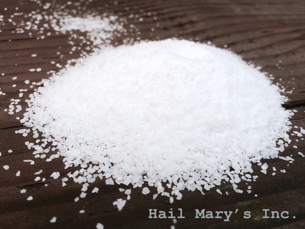 A pile of white salt on a wooden table.