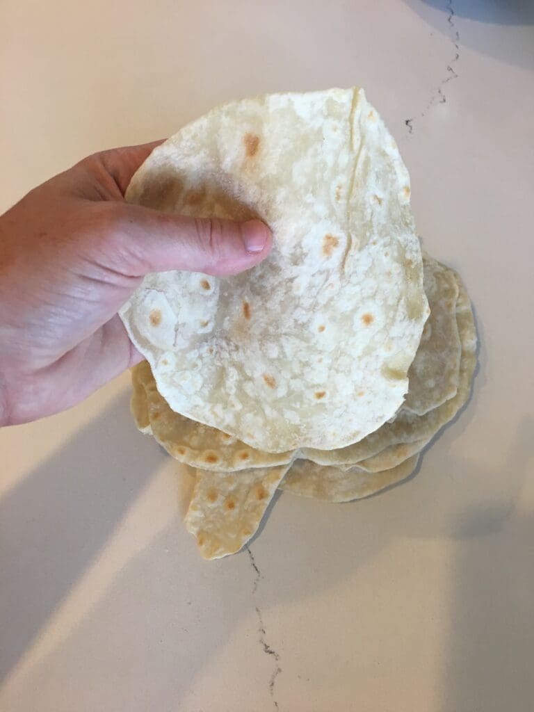 a hand holding a flour tortilla