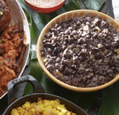 A bowl of black beans and rice on a green leaf.
