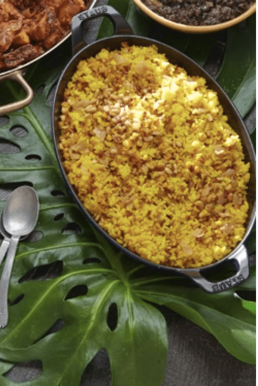 A plate of yellow rice and other dishes on a table.