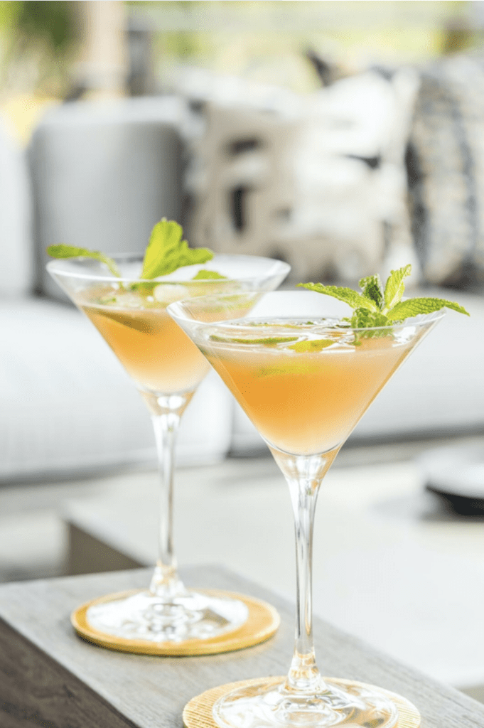 Two martinis on a table with mint leaves.