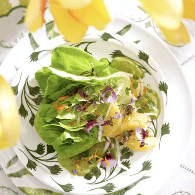 A plate with a lettuce salad and flowers on it.