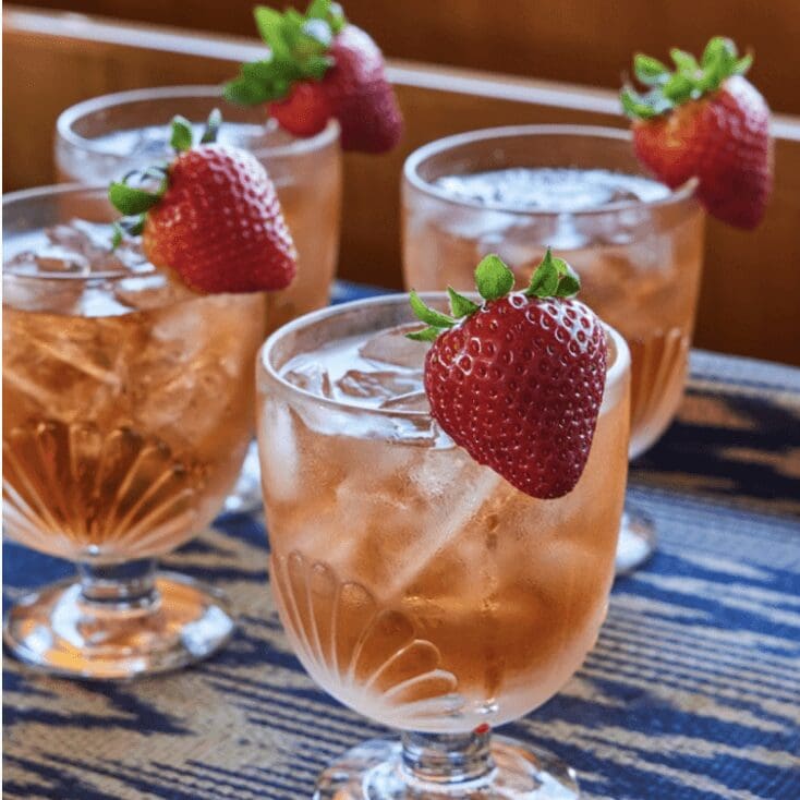 Three glasses of iced tea with strawberries on top.