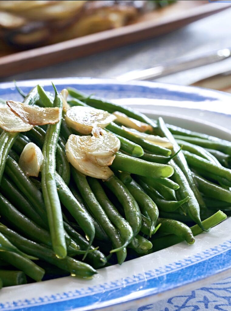Green beans with garlic on a blue and white plate.