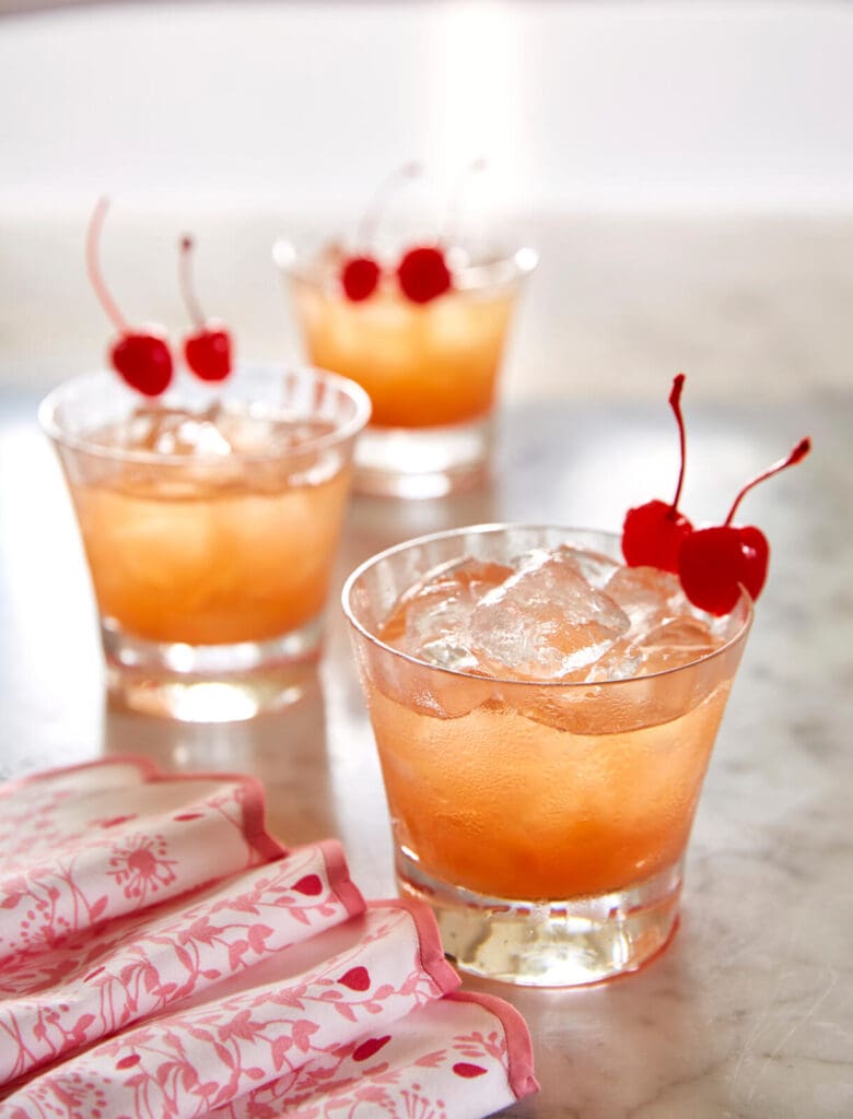 A cocktail with cherries and ice in a glass.