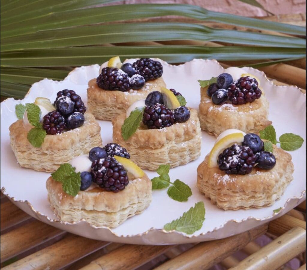 A plate of pastries with blackberries and lemons on it.