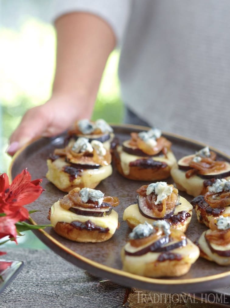 A person is holding a plate of appetizers with blue cheese and mushrooms.
