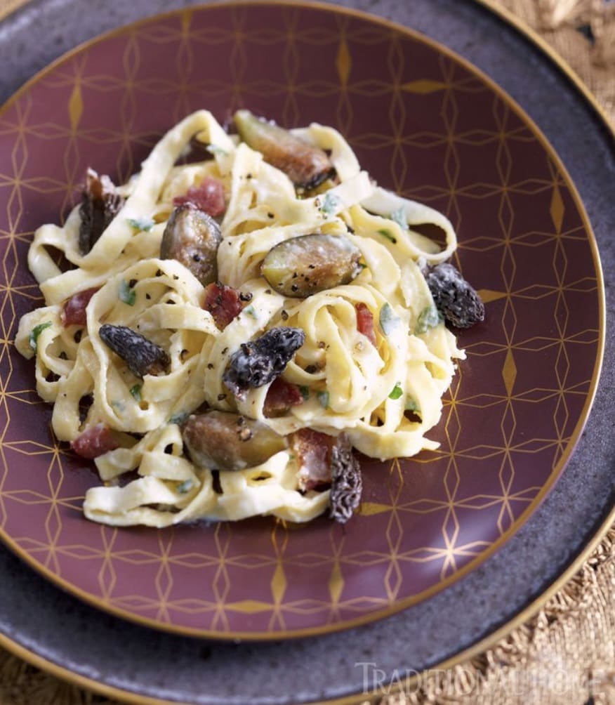 A plate of pasta with bacon and figs.