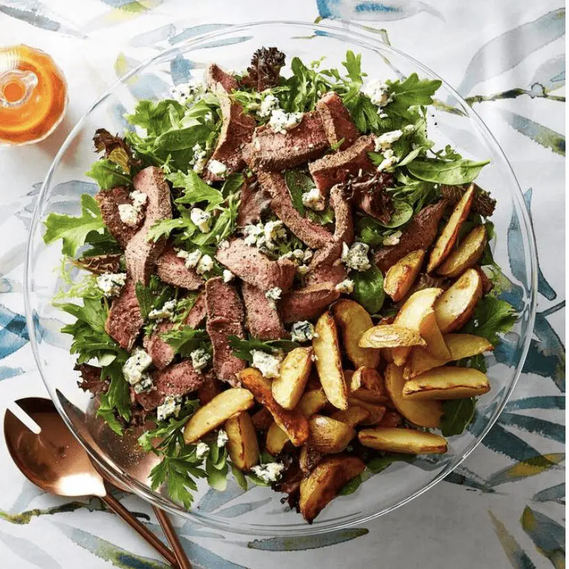 A salad with steak, potatoes and blue cheese.