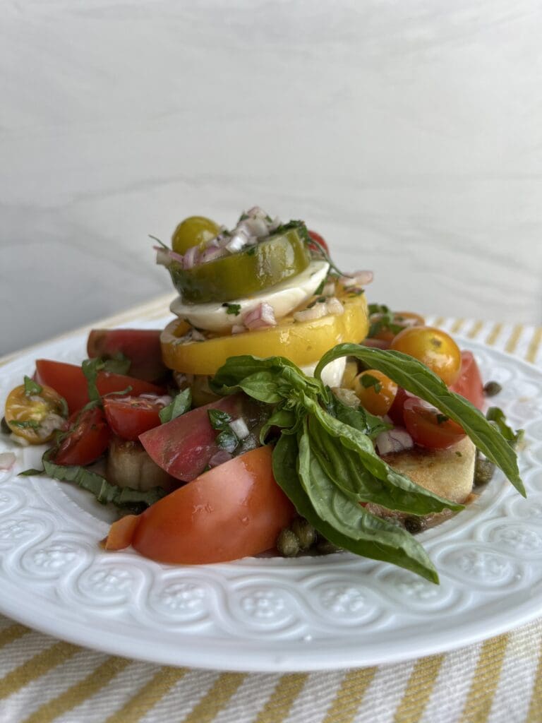 Fresh vegetable salad with tomatoes, cucumbers, and leafy greens on a white plate.