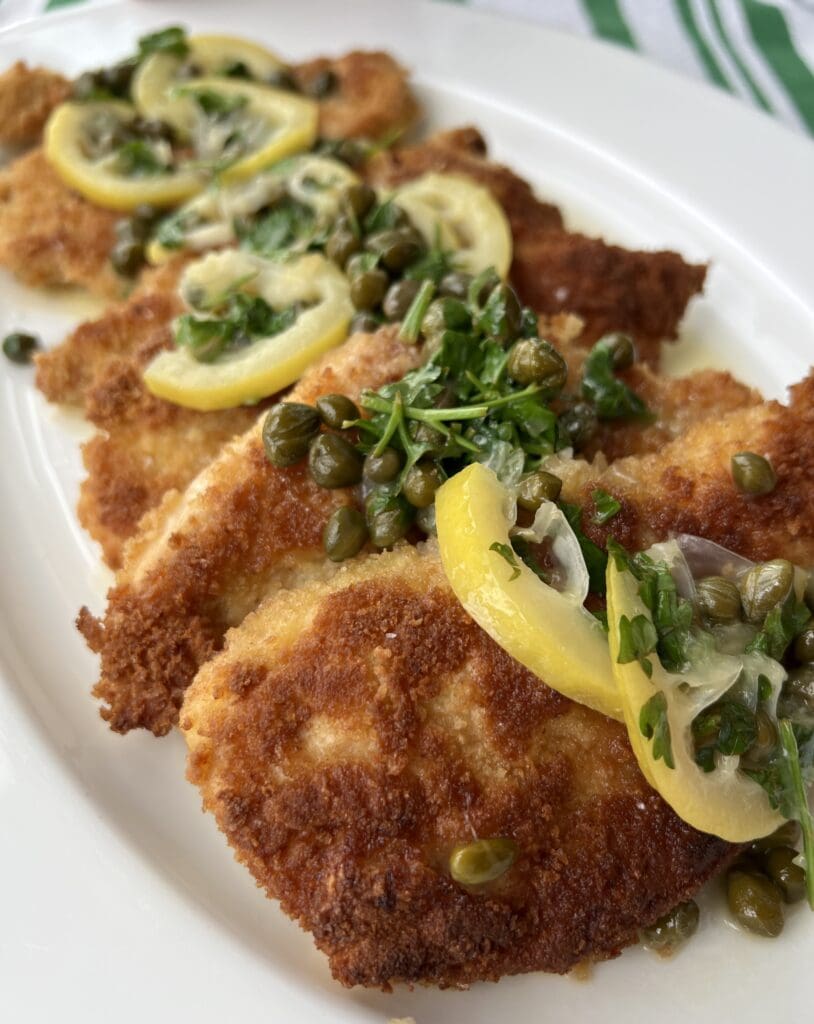 Breaded and fried fish fillets garnished with lemon slices and herbs.