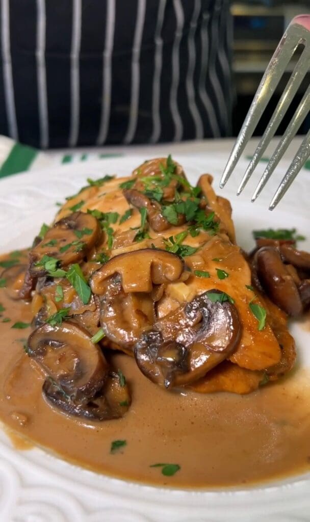 Close-up of savory mushroom-covered meat with herbs.