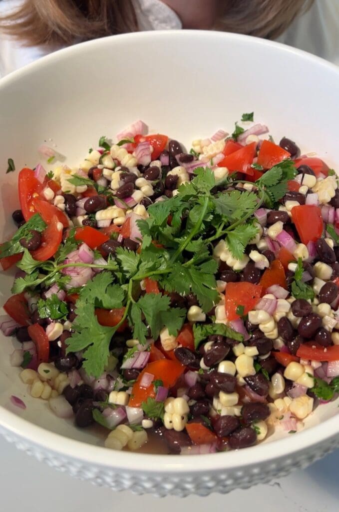 A fresh vegetable and corn salad with cilantro garnish.