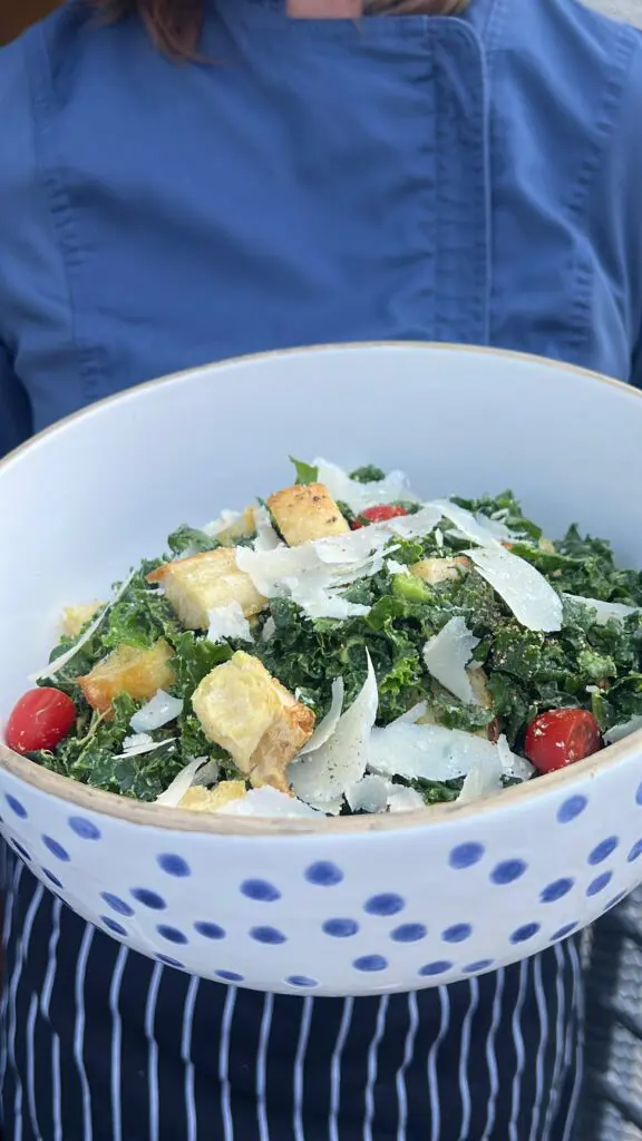 Fresh Caesar salad with croutons and cherry tomatoes in a white bowl.
