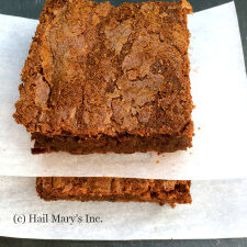 Two squares of chocolate brownies on a napkin.