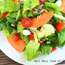 A simple salad with tomatoes, cucumbers, and carrots on a white plate - perfect for a quick and healthy meal.