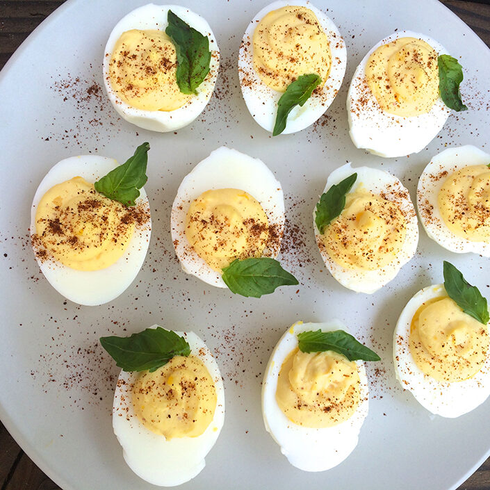 Deviled eggs on a plate with mint leaves.