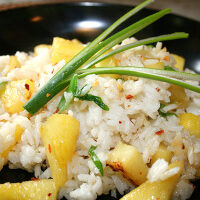 A black plate with rice and pineapple.