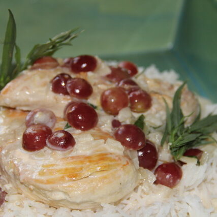Chicken with grapes and rice in a green bowl.