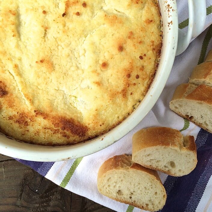 A bowl of food next to a piece of bread.