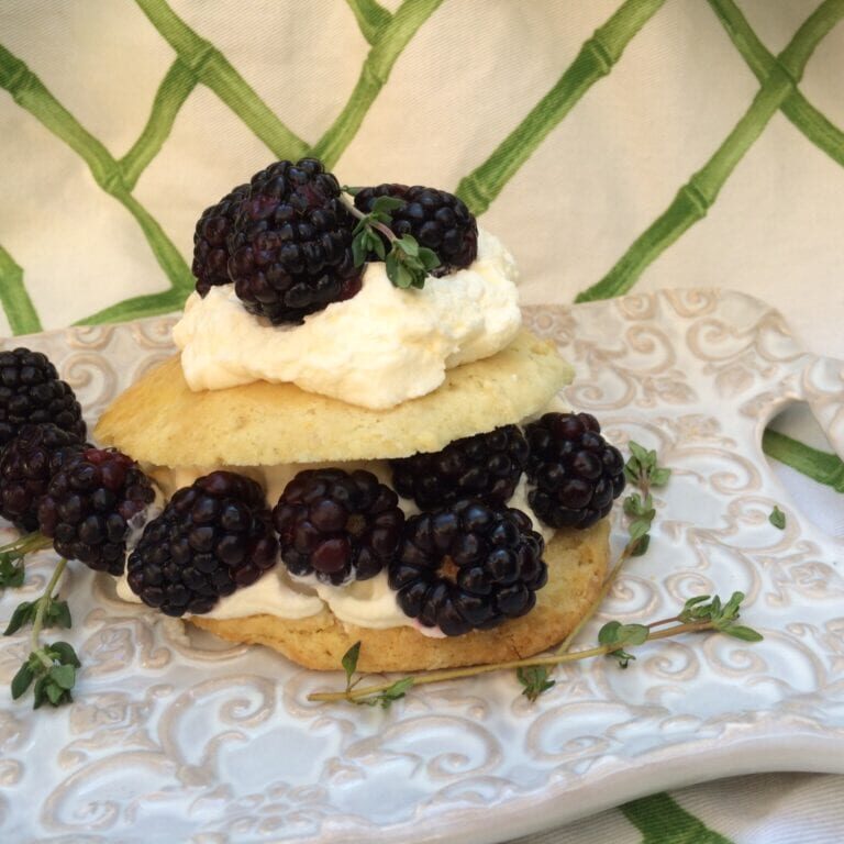 Delicious blackberry biscuits topped with whipped cream and thyme, perfect for summer desserts.