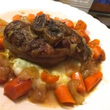 A plate with pork, carrots, and mashed potatoes.