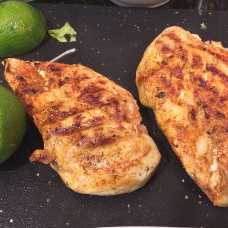 two grilled chicken breasts with sliced lime