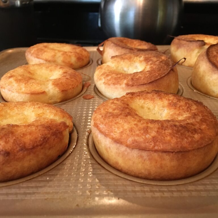 A tray of muffins sitting on top of a stove, perfect for your next popover recipe.