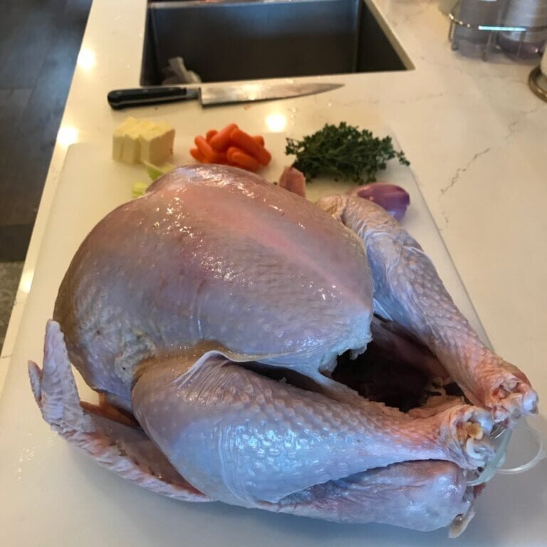 Get ready for Thanksgiving with these DIY turkey tips! A turkey is sitting on a cutting board in a kitchen.
