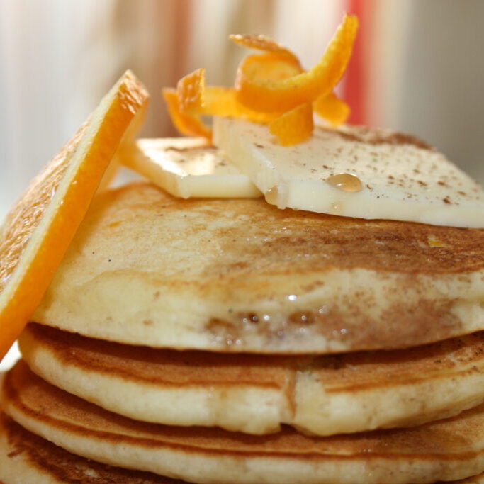 A stack of orange pancakes on a plate.