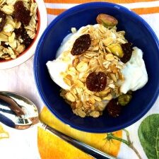 A bowl of homemade granola with yogurt and oranges.