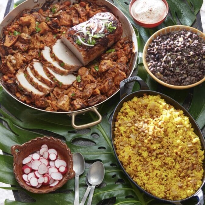 A plate of mexican food on a table with a palm leaf.