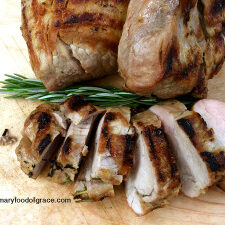 Grilled pork chops on a cutting board with rosemary sprigs, a perfect addition to your grilled meal.