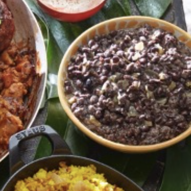 A bowl of black beans and rice on a green leaf.