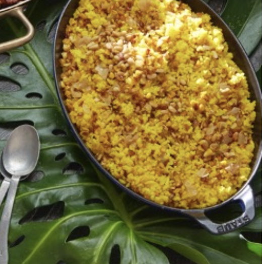 A plate of yellow rice and other dishes on a table.