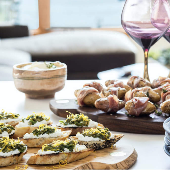 A plate of appetizers on a table next to a glass of wine.