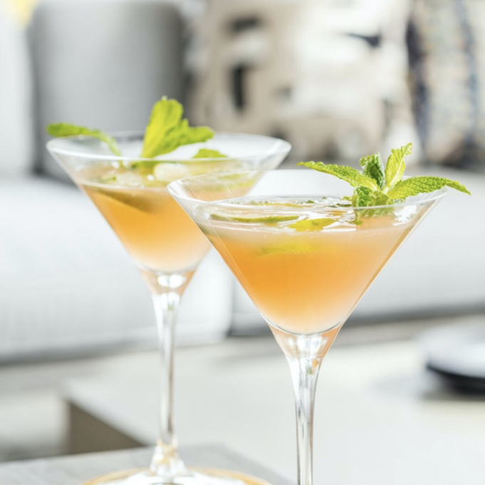 Two martinis on a table with mint leaves.