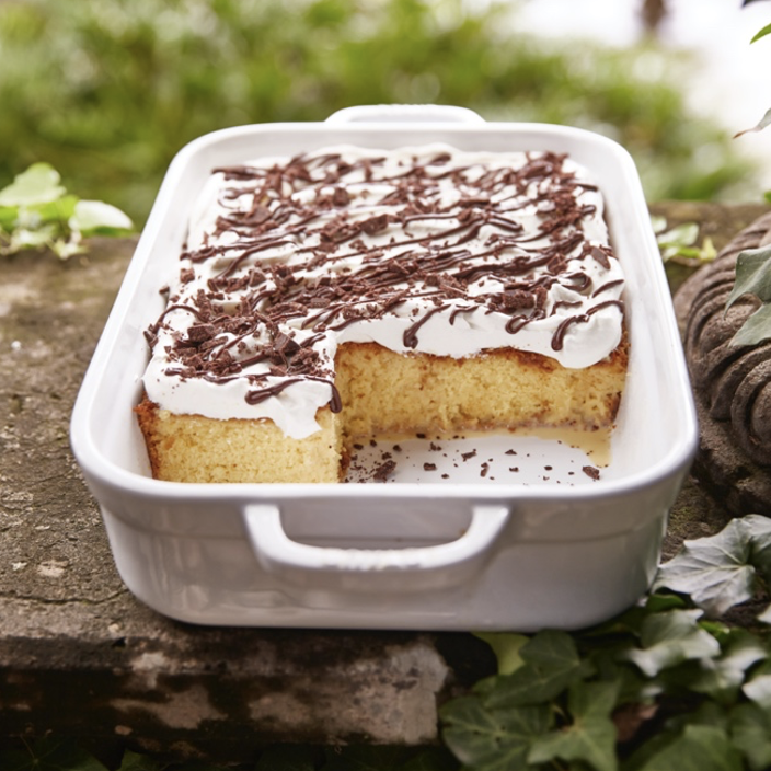 A white dish with a piece of cake on it.