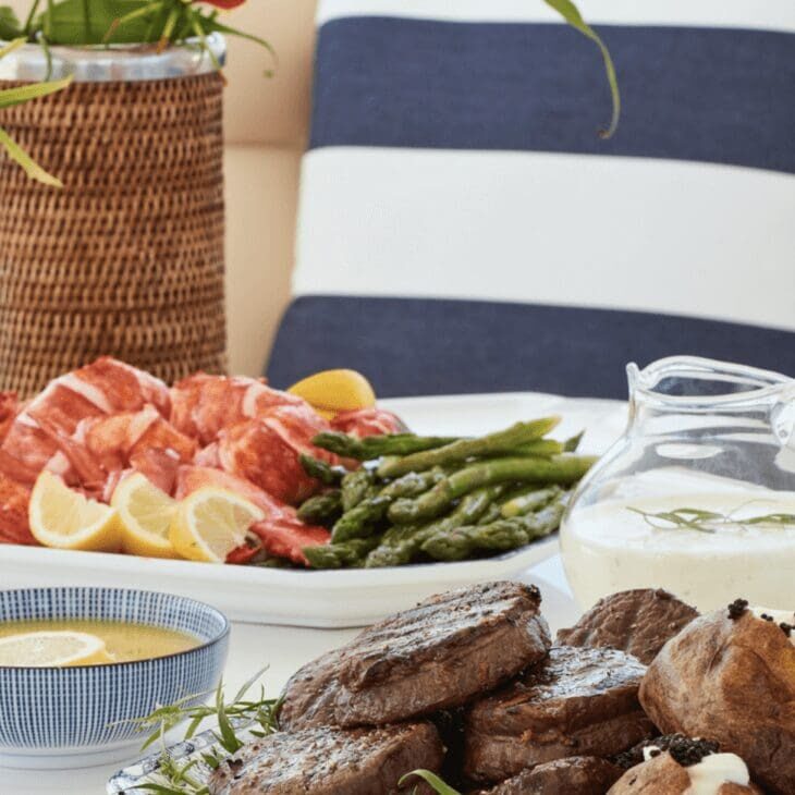 A table with steaks, asparagus, and lemons.