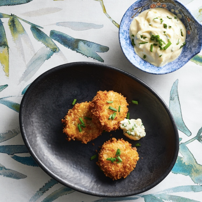 A plate with crab cakes and a bowl of dipping sauce.